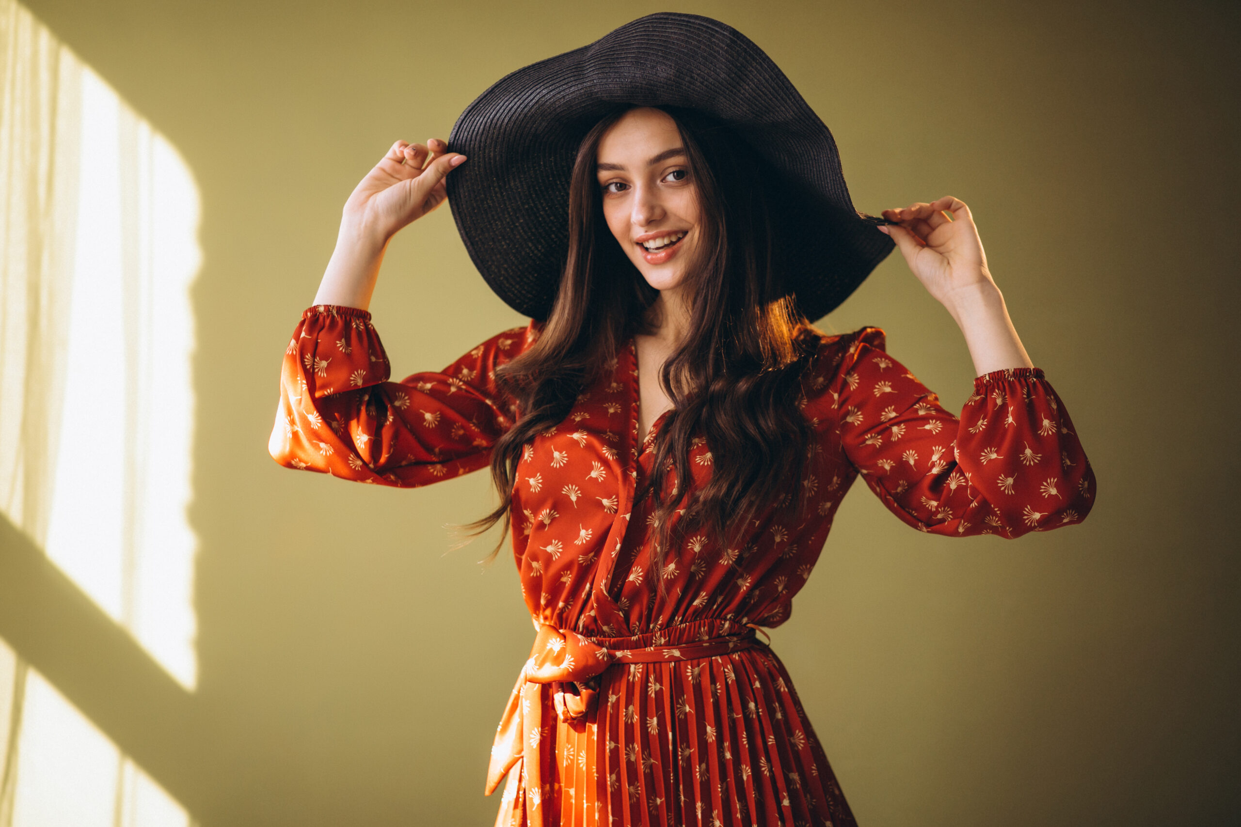 Young woman in a beautiful dress and hat in studio